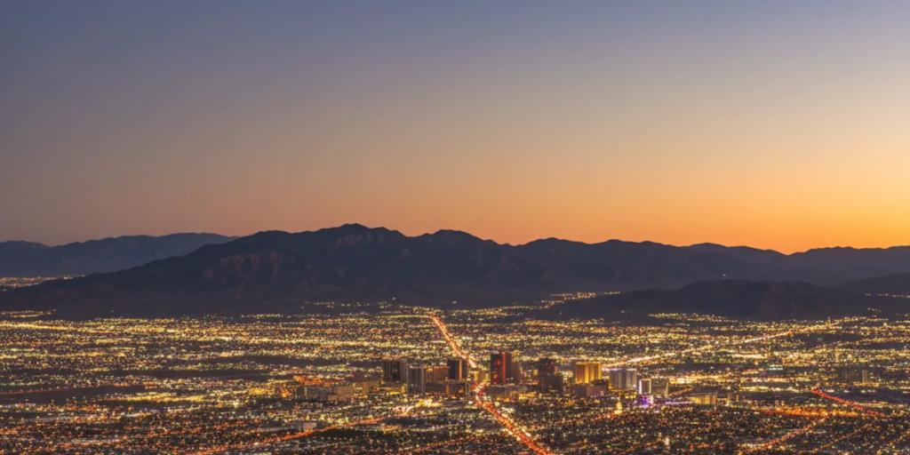 La vallée désertique de Las Vegas rougeoyant au crépuscule, les tours au néon du Strip s'élevant du Mojave