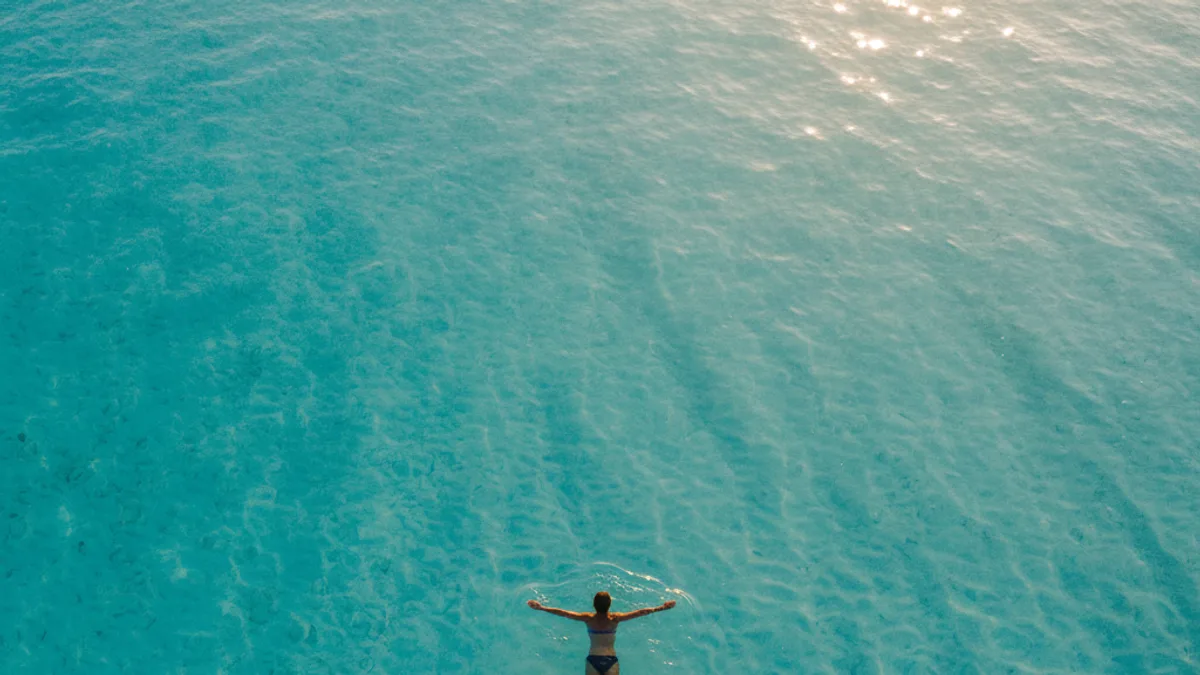 Nageur flottant sur le dos dans des eaux turquoise et limpides, photographié du dessus